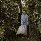 a boy in a suit and tie is carrying a large bag