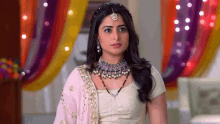 a woman wearing a necklace and earrings is standing in front of a colorful background