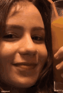 a girl with a nose ring holds a glass of orange juice