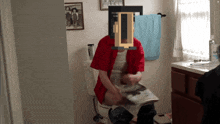 a man in a red shirt sits on a toilet