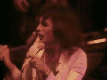 a woman is singing into a microphone on stage .