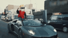 a man wearing a crown and sunglasses is driving a black lamborghini .