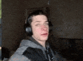 a young man wearing headphones is making a funny face in a dark room .