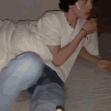 a man wearing a white shirt and ear buds is laying on a bed