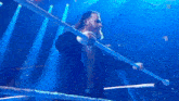 a man with a beard is standing in a wrestling ring holding a bar .