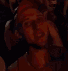 a man wearing a red hat and a red tank top is standing in a crowd of people .