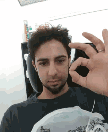 a man with a beard is making an ok sign with his hands .