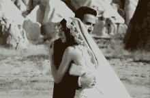 a black and white photo of a bride and groom hugging .