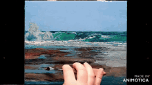 a person is painting a picture of the ocean and the words made in animatica are visible