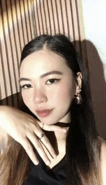 a woman with long hair is wearing a black shirt and earrings .