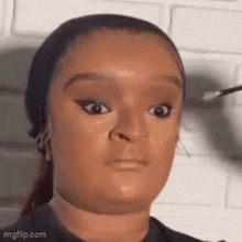 a woman is applying makeup to her face while making a funny face .