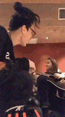 a man wearing a black shirt with the number 25 on it is playing a guitar