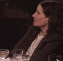 a woman is sitting at a table with glasses of wine and a caption that says ' oops '