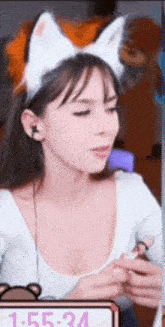 a woman wearing a cat ear headband and headphones is sitting in front of a clock .