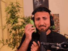 a man wearing headphones is singing into a microphone and holding a cucumber .