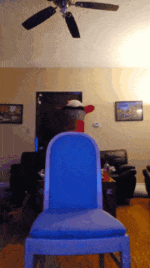 a blue chair in a living room with a ceiling fan above it