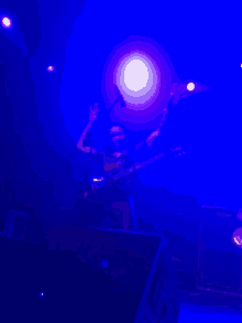 a man playing a guitar in a dark room with blue lights behind him