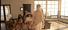 a woman in a baseball cap is standing in a living room surrounded by women