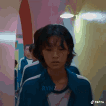 a woman in a blue jacket is walking down a hallway next to other people .