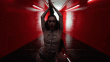 a woman in a lace up top and shorts is dancing in a red room .