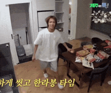 a man in a white shirt is dancing in a room with korean writing on the floor