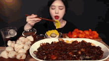 a woman eating a plate of food with chopsticks and a glass of cola