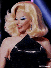 a woman with blonde hair wearing a black dress and earrings is smiling