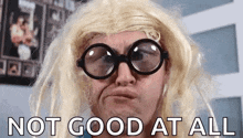 a man wearing glasses and a wig is making a funny face with the words `` not good at all '' behind him .