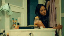 a woman is peeking out from behind a cabinet in a bathroom