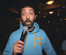 a man with a beard and a blue hoodie is holding a microphone