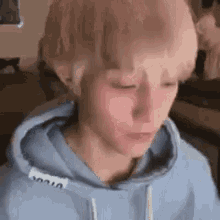 a close up of a person wearing a blue hoodie with a hood .