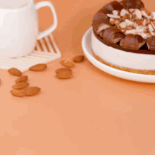 a piece of cake on a plate next to a cup of coffee and almonds