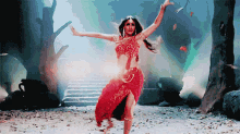 a woman in a red dress is dancing in the woods