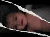 a baby is laying on a bed with a piece of paper behind it