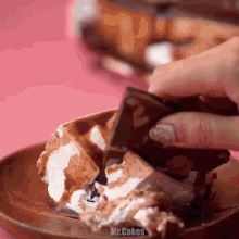 a close up of a person holding a piece of chocolate on a plate with mr.cakes written on the bottom