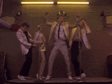 a group of men in suits and ties are dancing in front of microphones