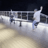 a man is sitting on a seesaw while another man stands behind him