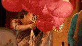 a woman is holding a bunch of red balloons in her hands