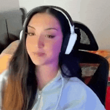 a woman wearing headphones is sitting in a chair and making a funny face .