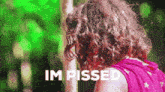 a girl with curly hair is standing in front of a sign that says im pissed