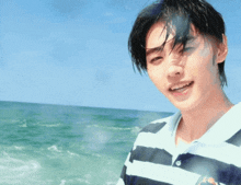 a young man wearing a striped shirt is standing on the beach