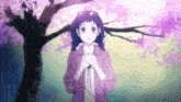 a girl in a purple jacket is standing in front of a tree with pink flowers .