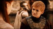 a young boy in a knight 's armor looks at a woman