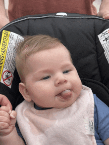 a baby in a car seat with a warning advertencia on the back