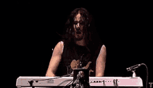 a man is playing a keyboard in front of a microphone with the letter t on the bottom right