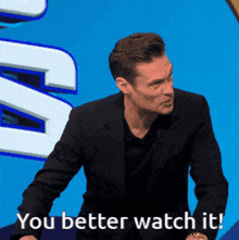 a man in a suit and black shirt says " you better watch it "