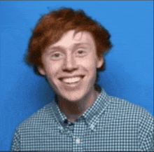 a man with red hair and a plaid shirt is smiling
