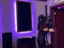 a man with dreadlocks is standing in front of a door with purple lights on the wall