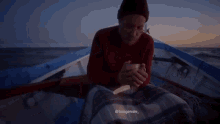 a man in a red sweater is sitting on a boat in the ocean .