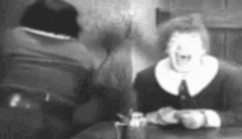 a black and white photo of a man and a woman sitting at a table